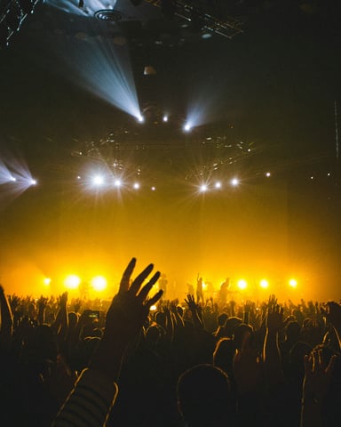 Concert crowd with hands raised under golden stage lights